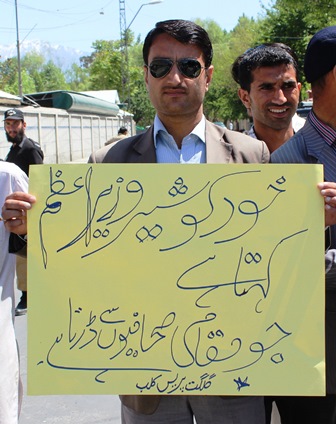 A journalist carrying a placard on which the PM has been taunted for calling himself a 'lion' and being afraid of the local journalists 