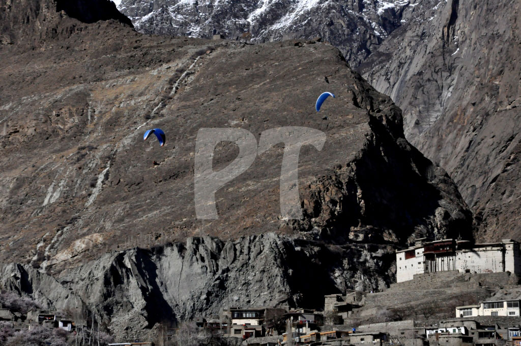 Two paragliders hover over the Baltit Town