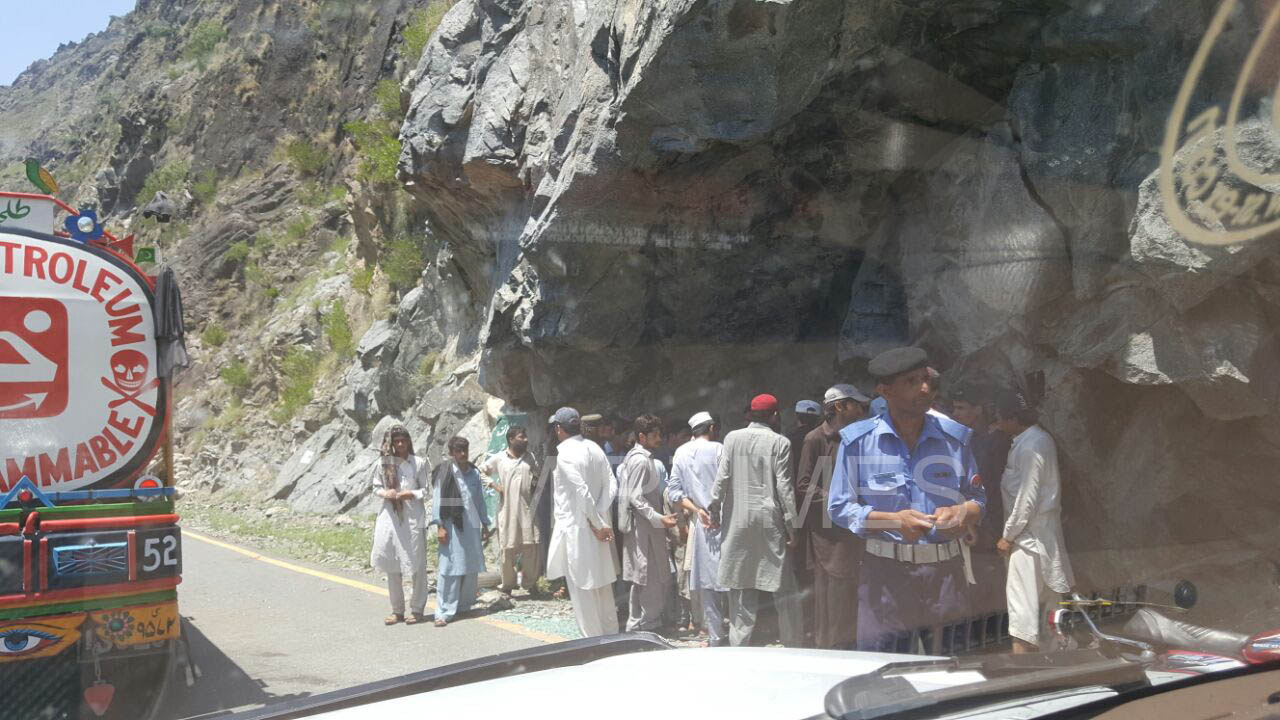 A group of locals surrounding a dead body recovered from the ravine. 